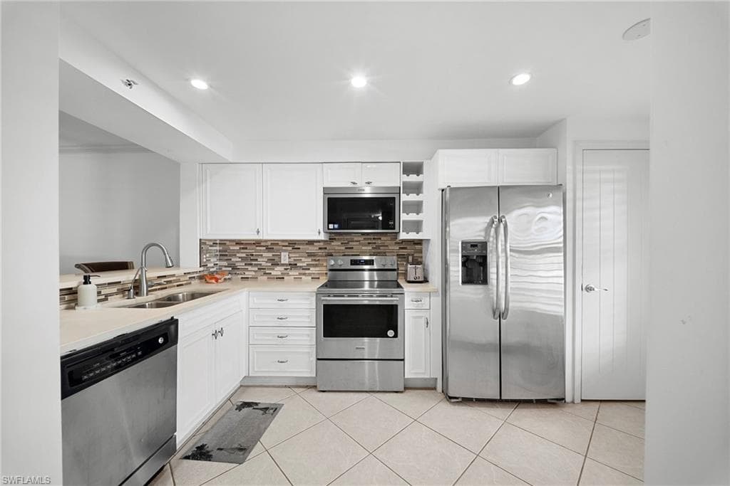 Kitchen featuring stainless steel appliances, white cabinetry, tasteful backsplash, and recessed lighting