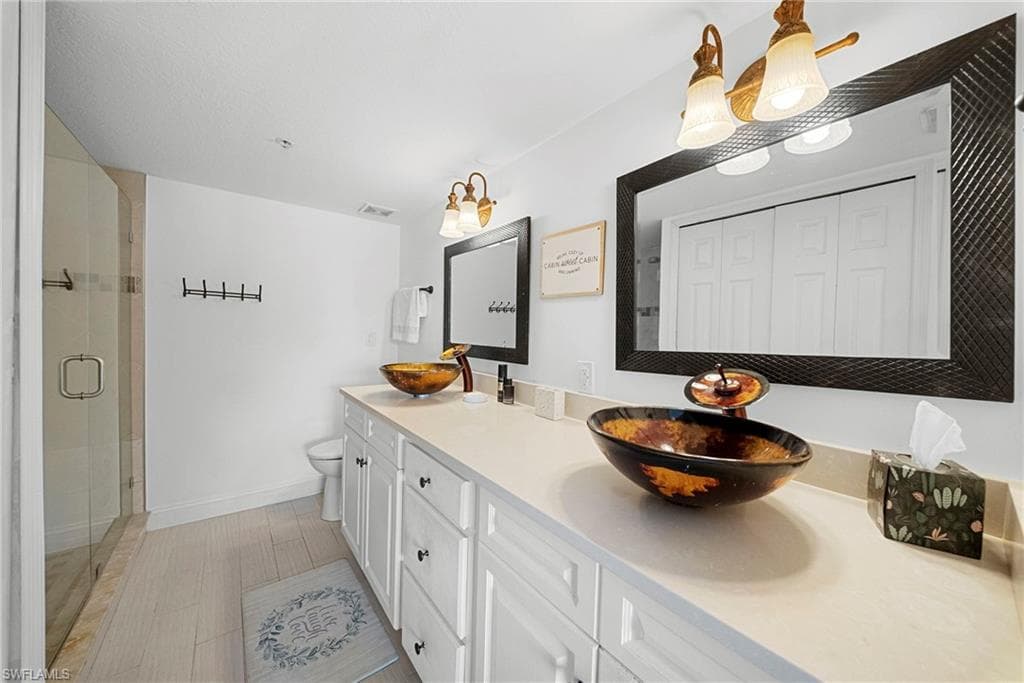 Full bathroom with double vanity, a shower stall, and a closet