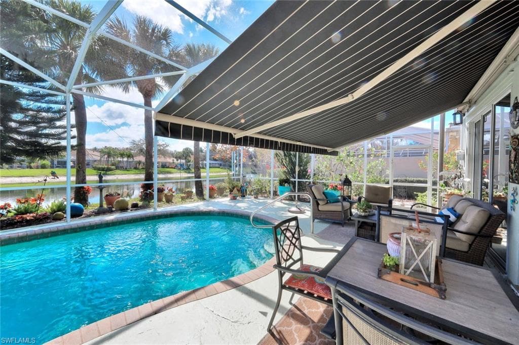Screened enclosure with a swimming pool, shaded patio area, and retractable awning