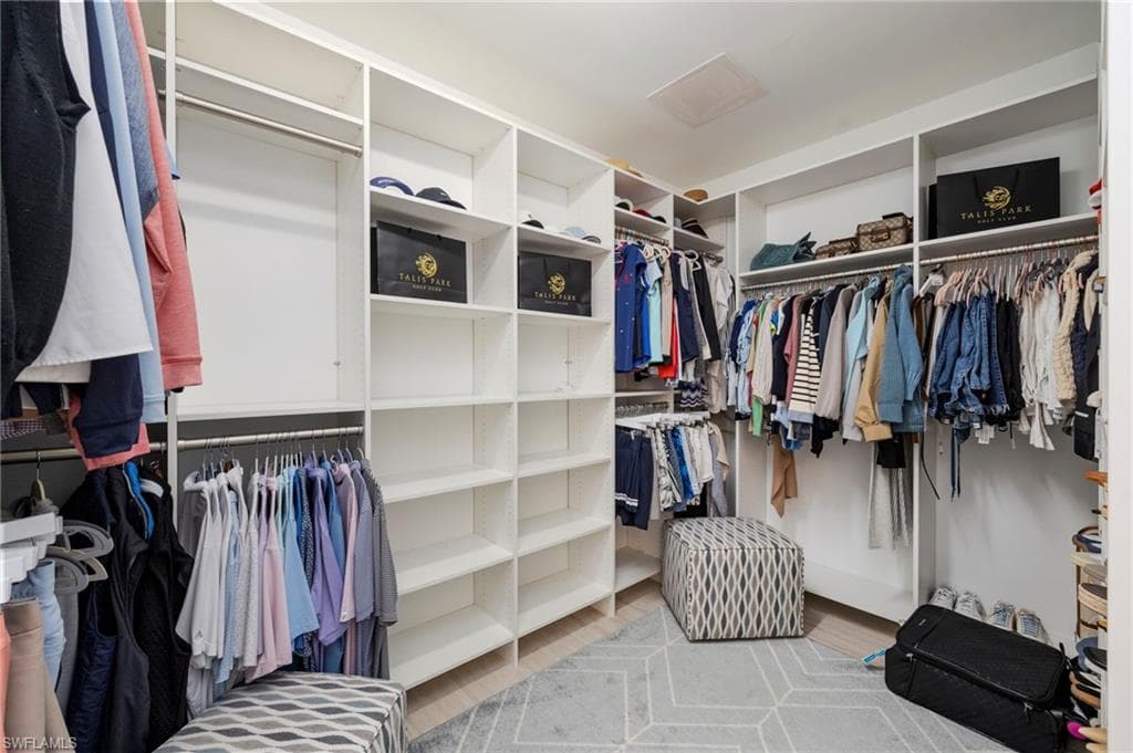 Walk in closet with attic access and light wood-style flooring
