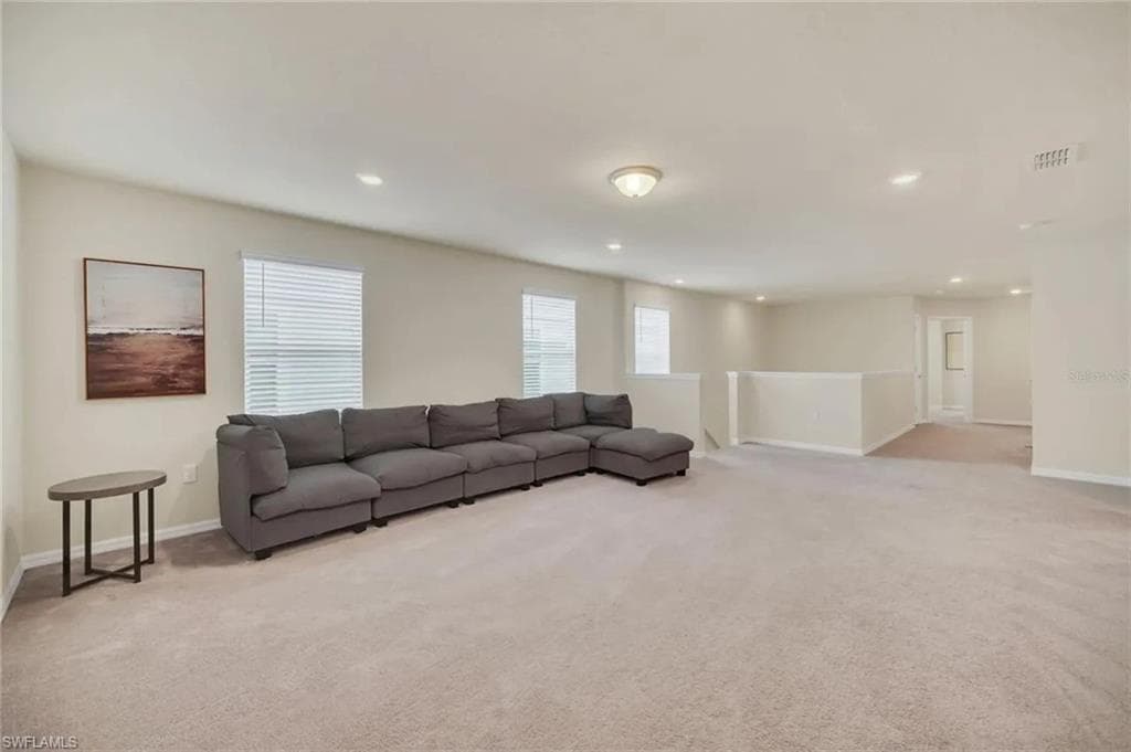 Living area featuring light colored carpet and recessed lighting