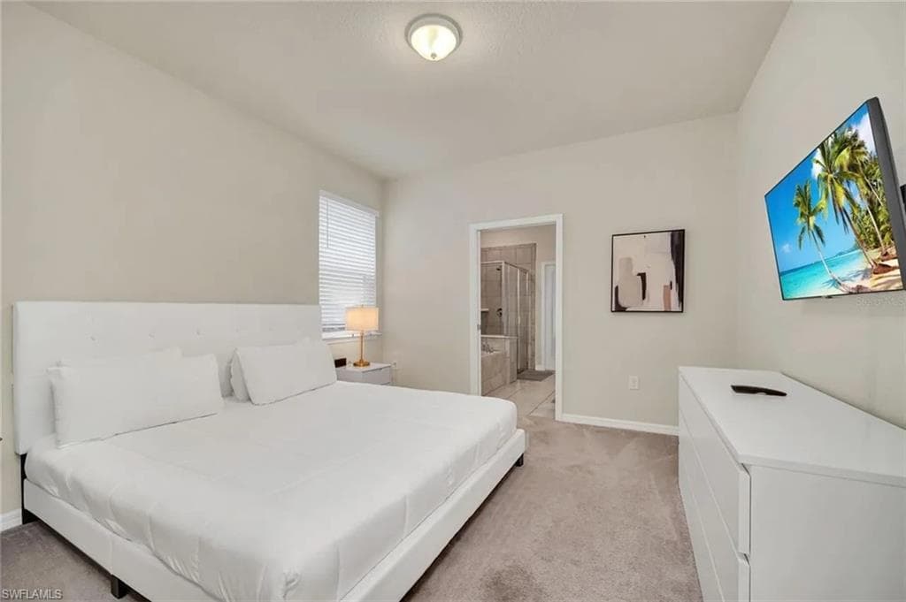 Bedroom featuring ensuite bathroom and light colored carpet