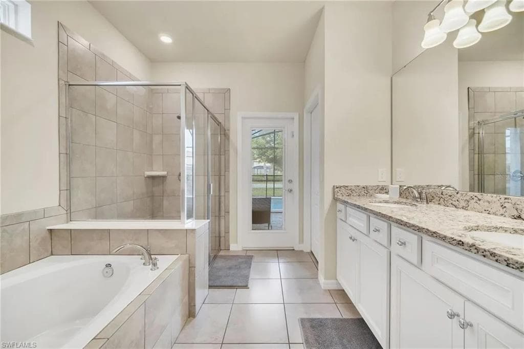 Full bathroom featuring double vanity, light tile patterned flooring, a shower stall, and a bath