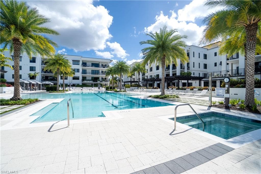 Expansive outdoor aquatic area featuring a large swimming pool, an integrated spa, and surrounding paver decking