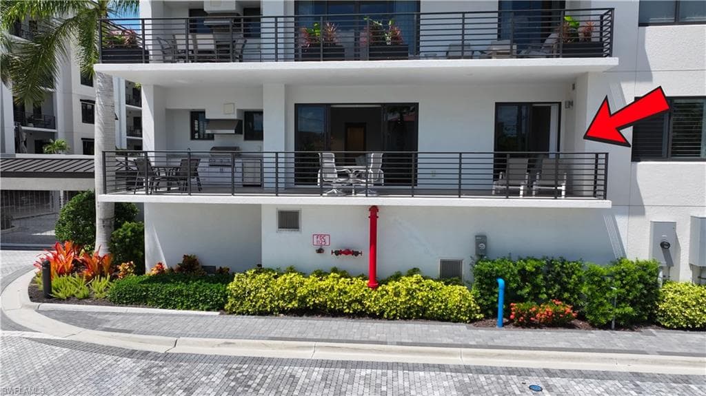 Upper-level balcony featuring contemporary horizontal metal railings, built-in outdoor grill station, and glass sliding door access