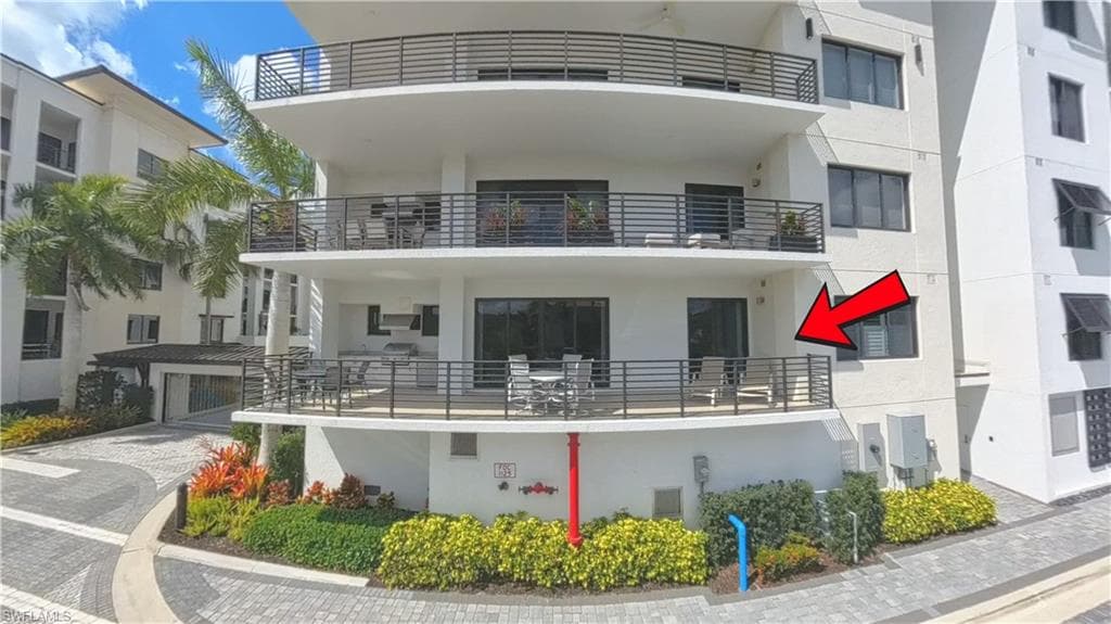 Spacious private balcony with black horizontal railings, an outdoor kitchen featuring a built-in grill, and ample space for outdoor dining