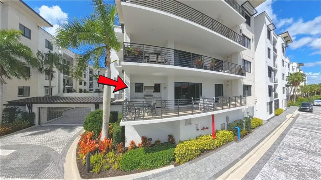 Expansive outdoor patio featuring an integrated built-in grill station, sleek metal railings, and direct access to an interior space via large sliding glass doors