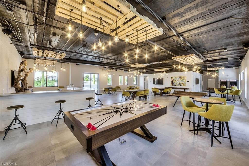 Spacious amenity room featuring industrial-style exposed ceiling, recessed lighting, and large format tile flooring