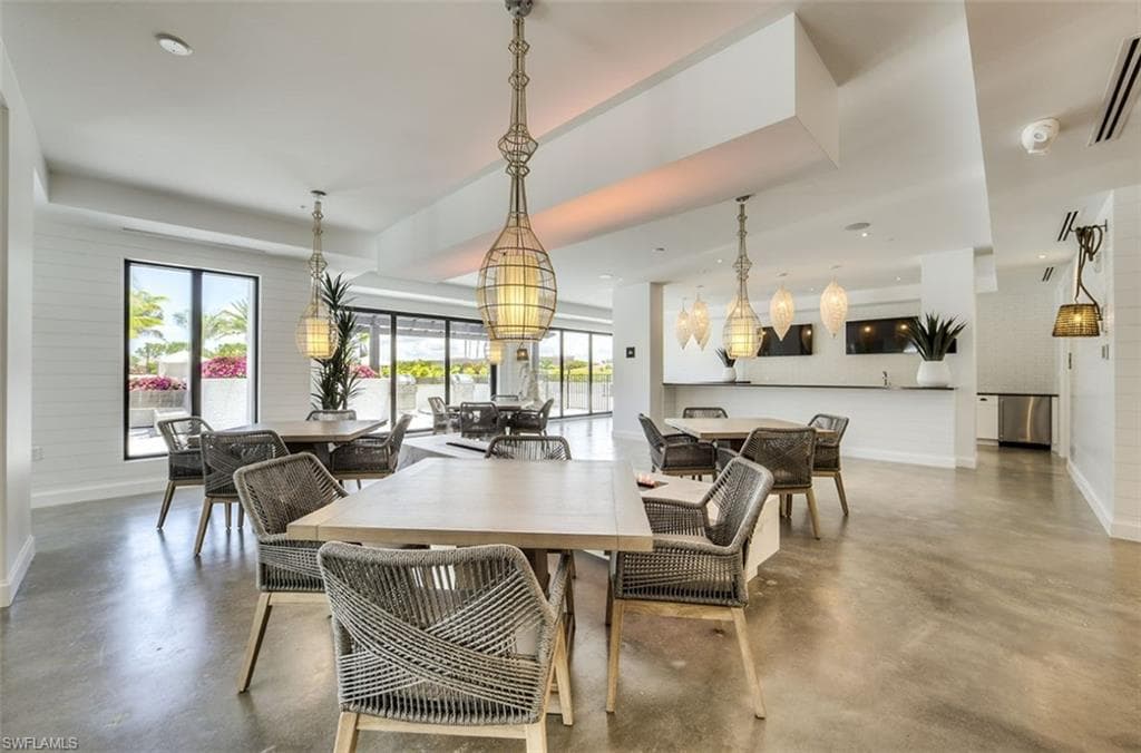 Interior gathering space featuring concrete-finish flooring, multiple dining areas, and a service bar with stainless steel appliances