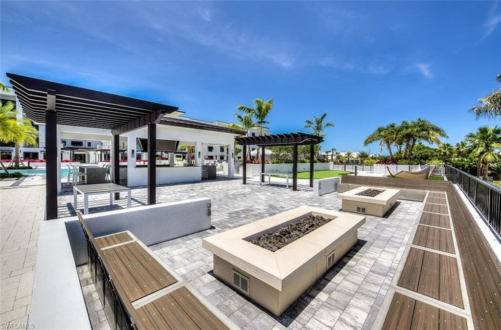 Expansive outdoor patio featuring multiple fire pits, integrated bench seating with wood-finish accents, and paver flooring