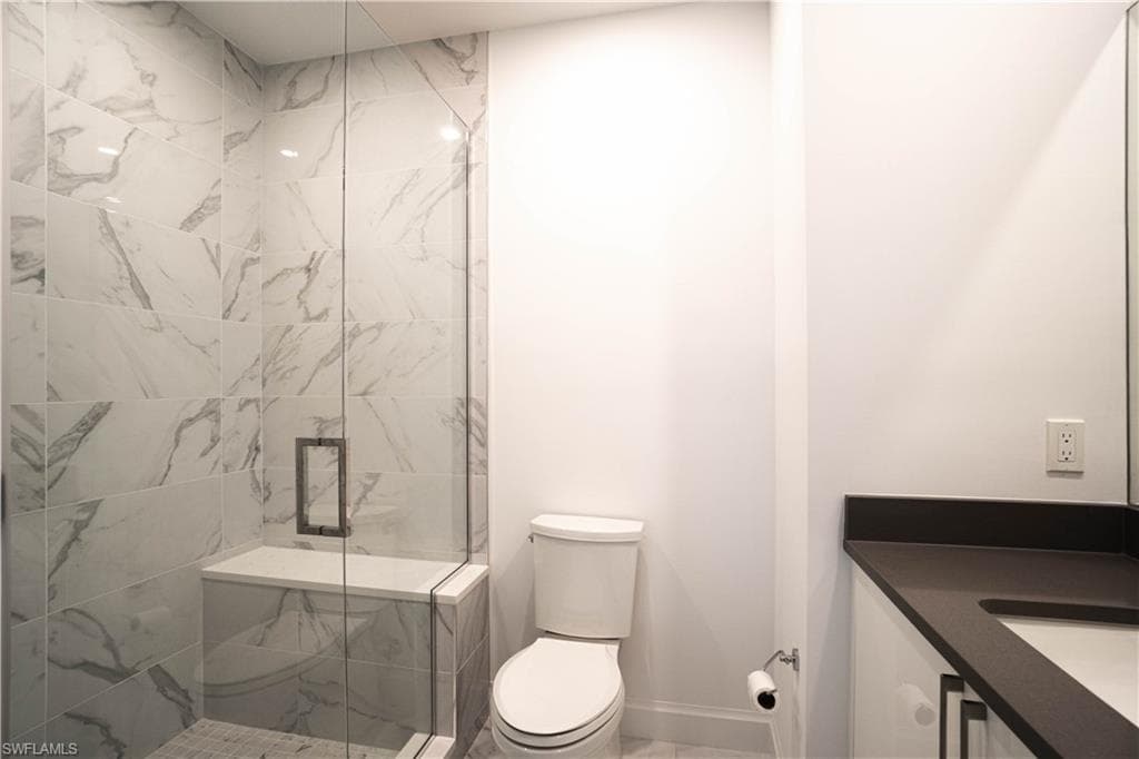 Bathroom with vanity and a marble finish shower