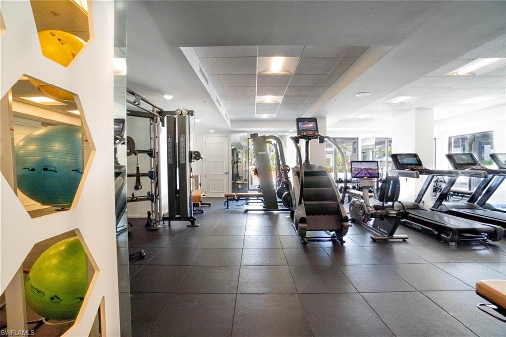 Fitness center featuring rubber flooring, recessed lighting, and a variety of exercise equipment including treadmills, stair climbers, and weight machines