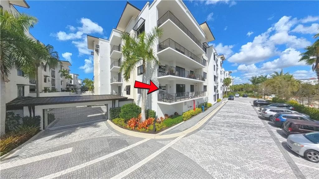 Modern multi-story building featuring white exterior walls and multiple private balconies with dark railings
