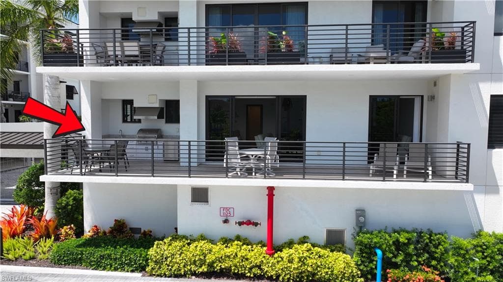 Spacious outdoor balcony featuring an integrated outdoor kitchen with a built-in grill and stainless steel hood