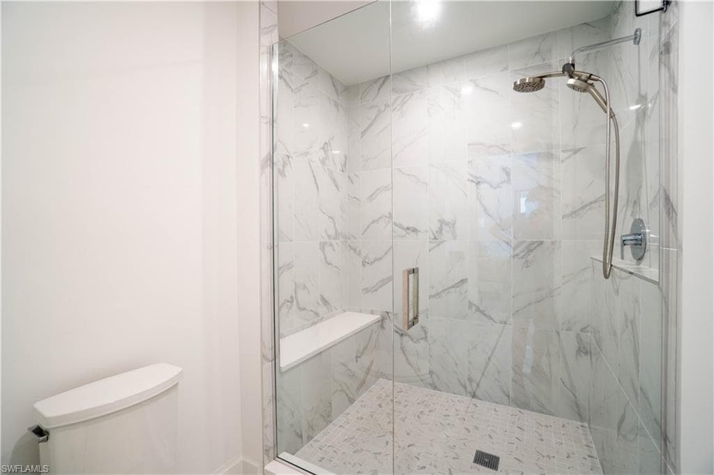 Bathroom featuring a marble finish shower and toilet
