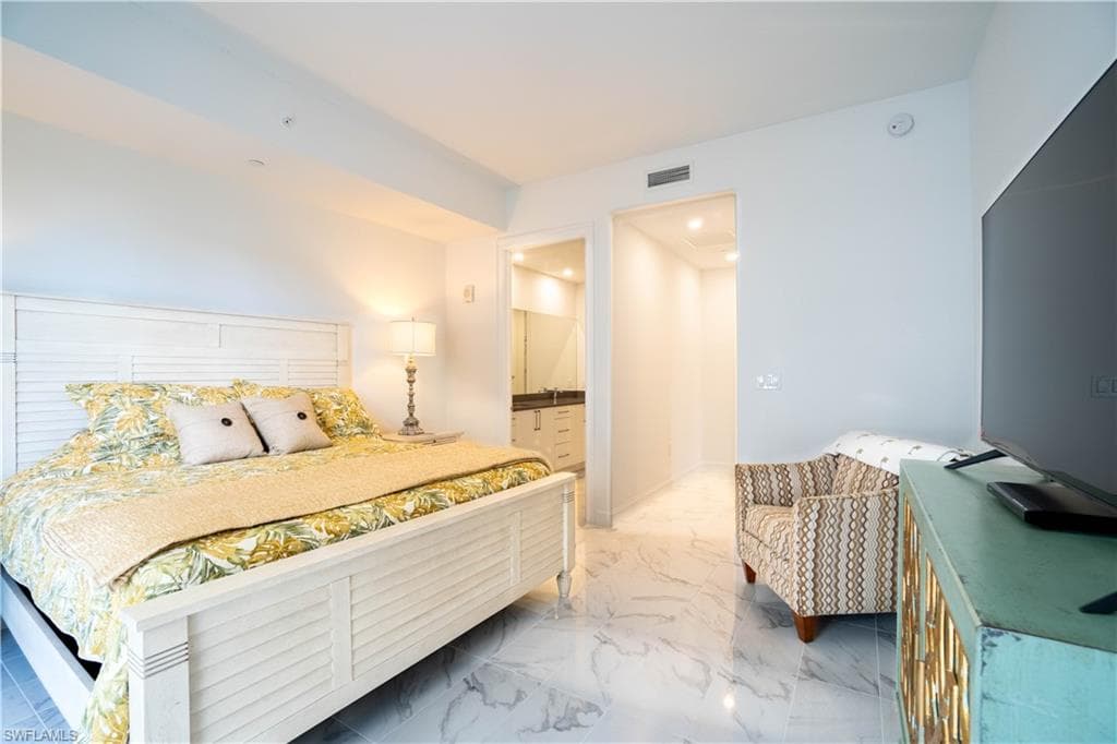 Bedroom featuring ensuite bath and light marble finish floors