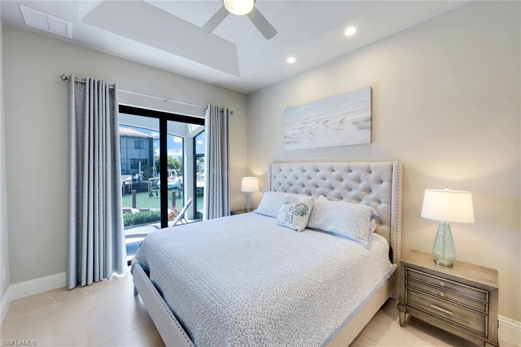 Bedroom featuring access to outside, ceiling fan, recessed lighting, a tray ceiling, and a water view