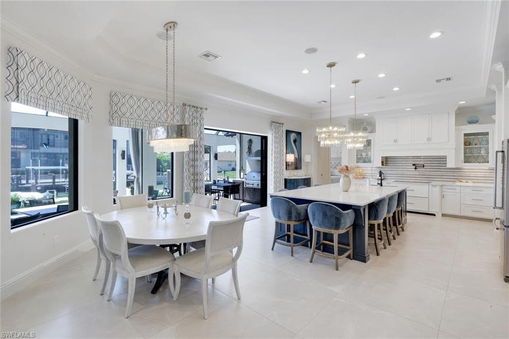 Dining area featuring a raised ceiling, a chandelier, ornamental molding, and light tile patterned flooring