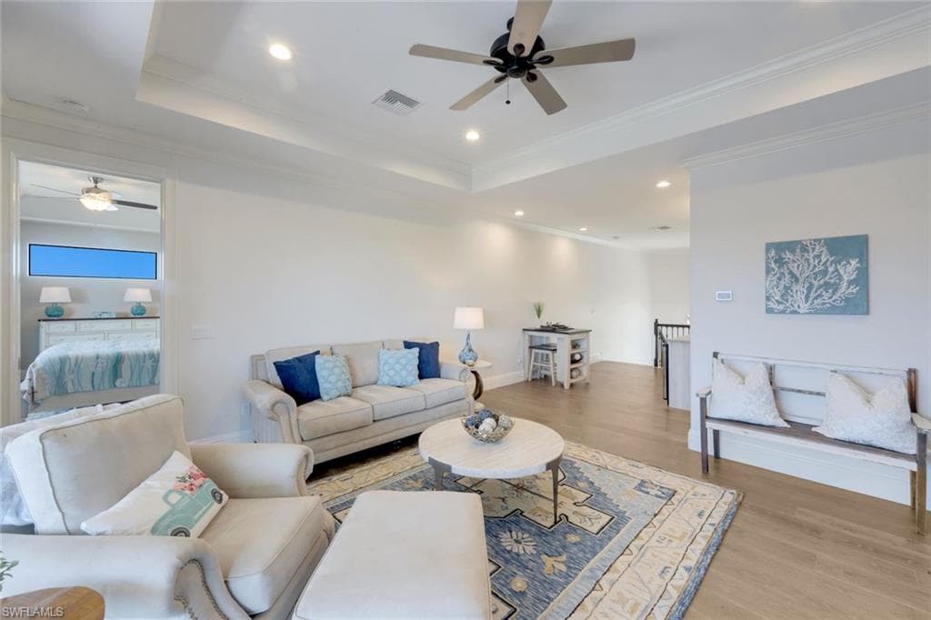 Living area with a ceiling fan, recessed lighting, light wood finished floors, a raised ceiling, and crown molding