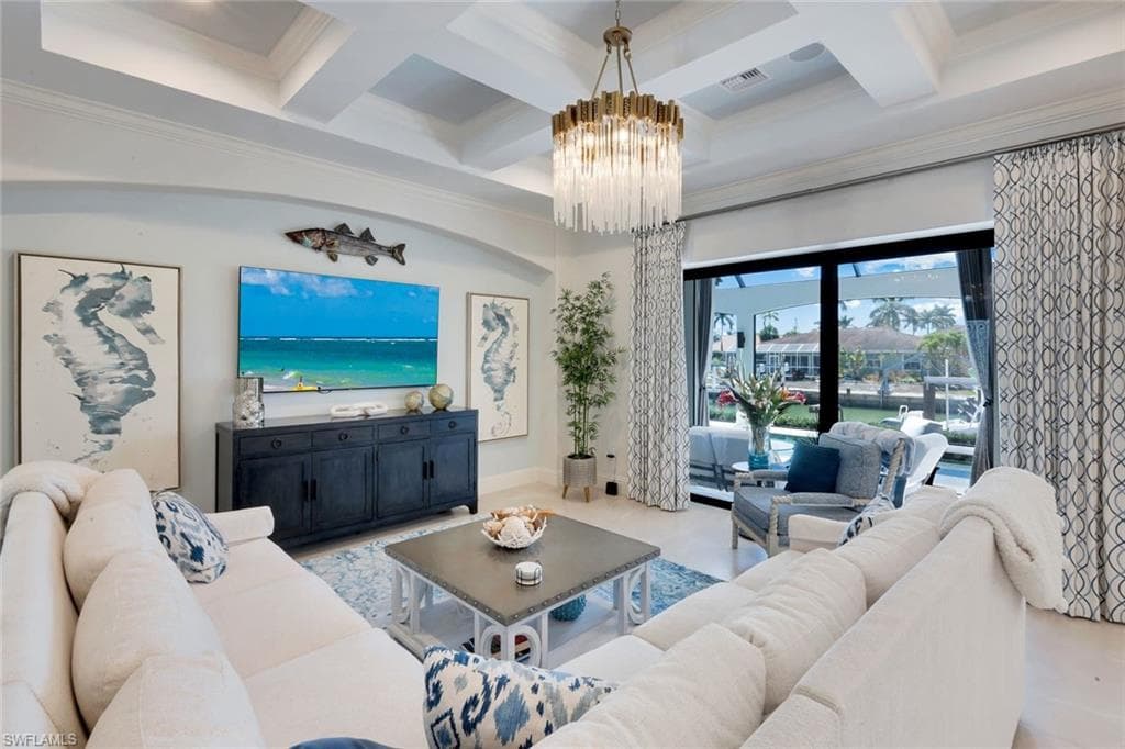 Living area with coffered ceiling, ornamental molding, and a chandelier