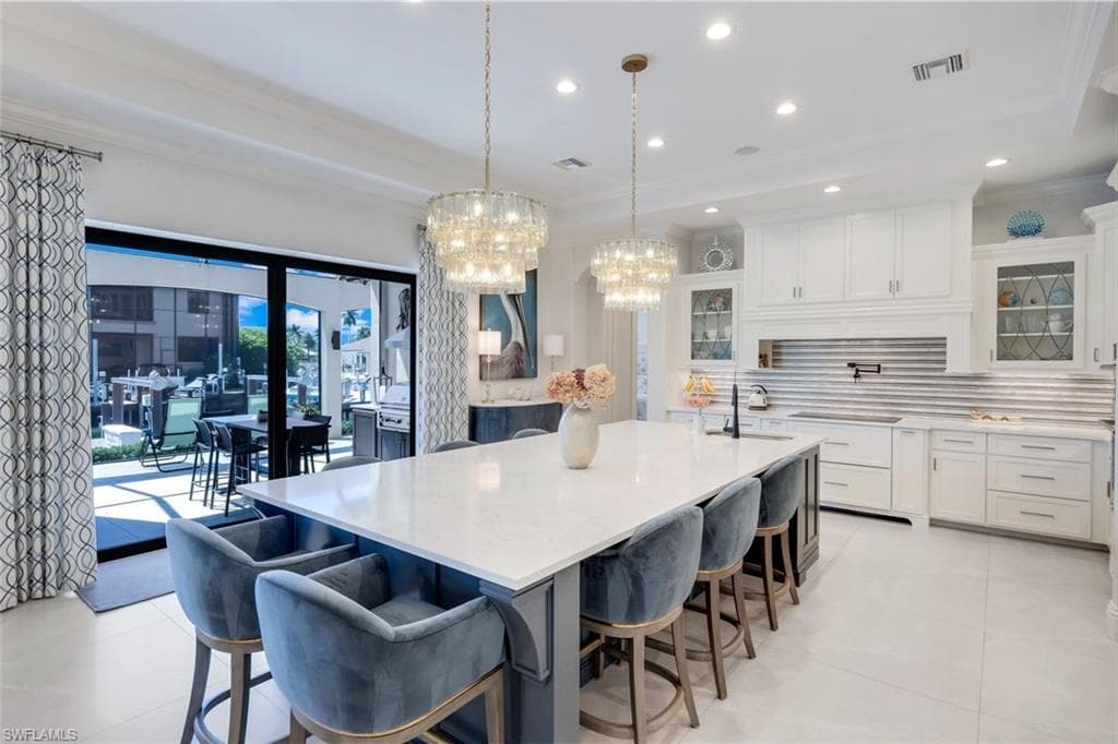 Kitchen with glass insert cabinets, a large island with sink, light stone counters, dual tone cabinetry, and a kitchen breakfast bar