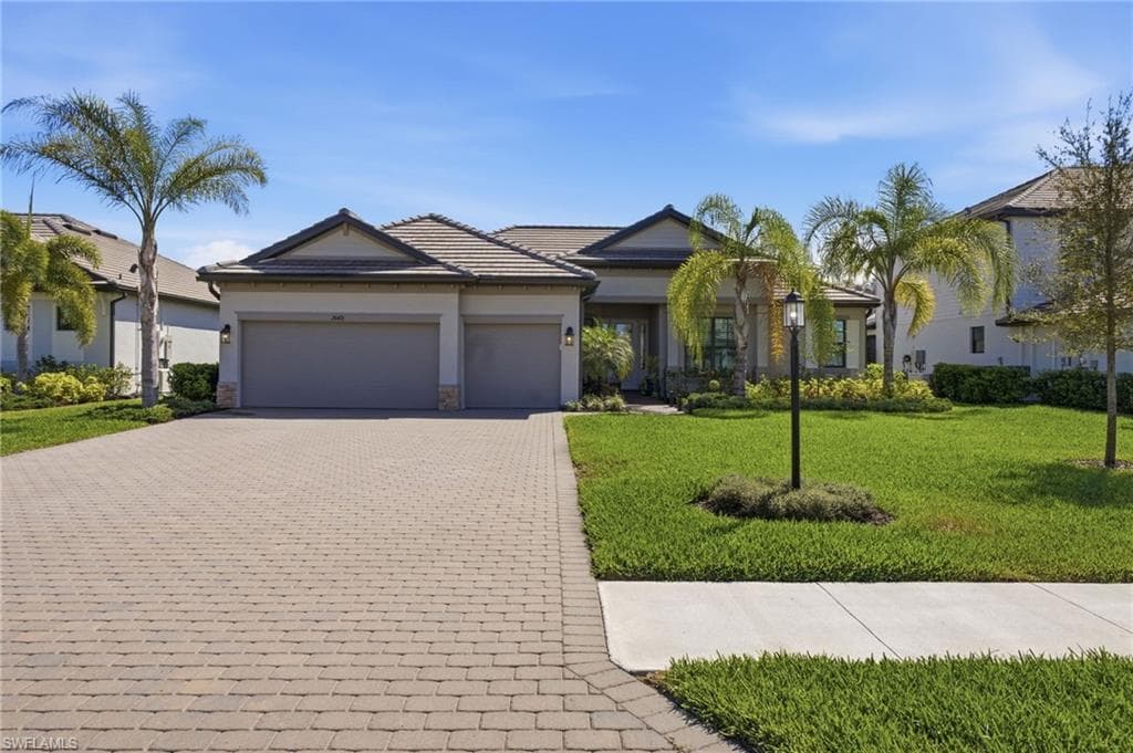 Ranch-style house with a front lawn, decorative driveway, a garage, stucco siding, and stone siding