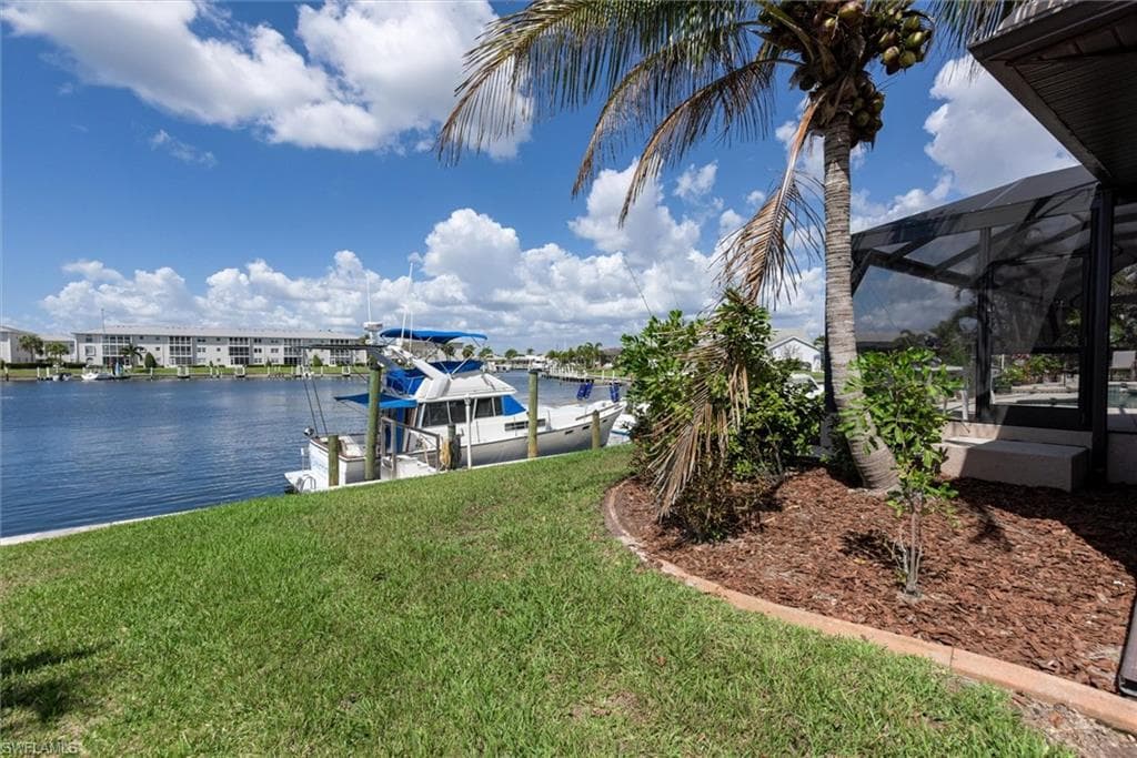 Dock area with a sunroom, a lanai, a yard, a water view, and boat lift