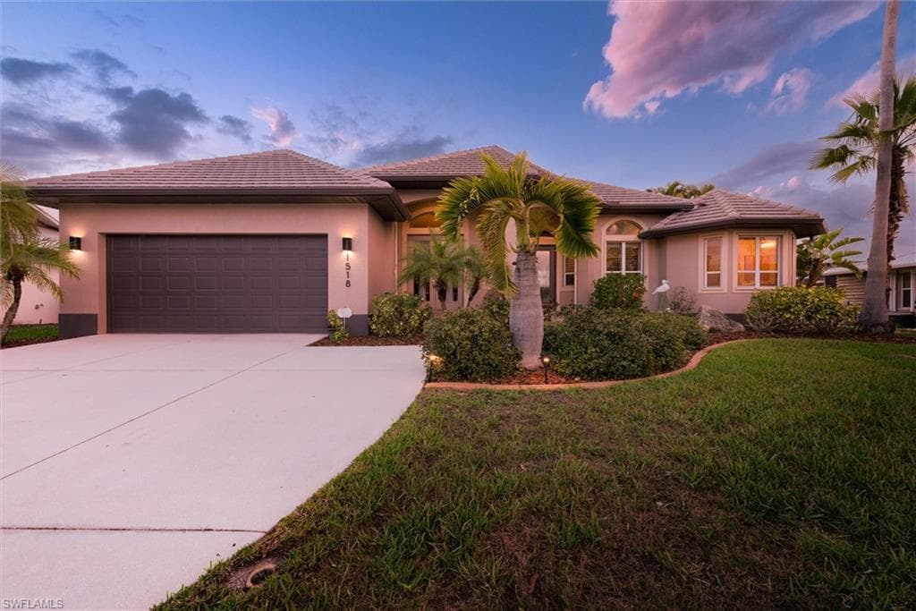 View of front facade with an attached garage, a tile roof, stucco siding, and concrete driveway