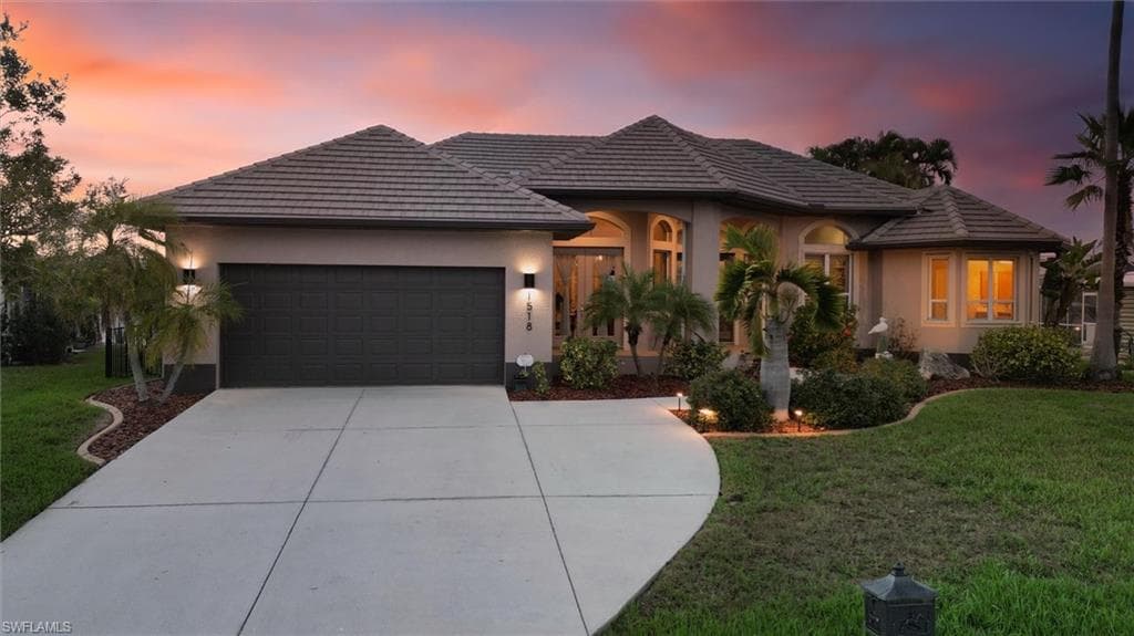 View of front of home with a front yard, a garage, concrete driveway, and stucco siding