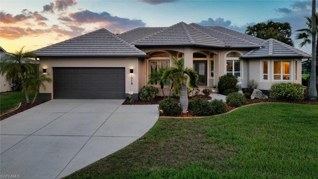 View of front of house featuring an attached garage, a yard, concrete driveway, and stucco siding