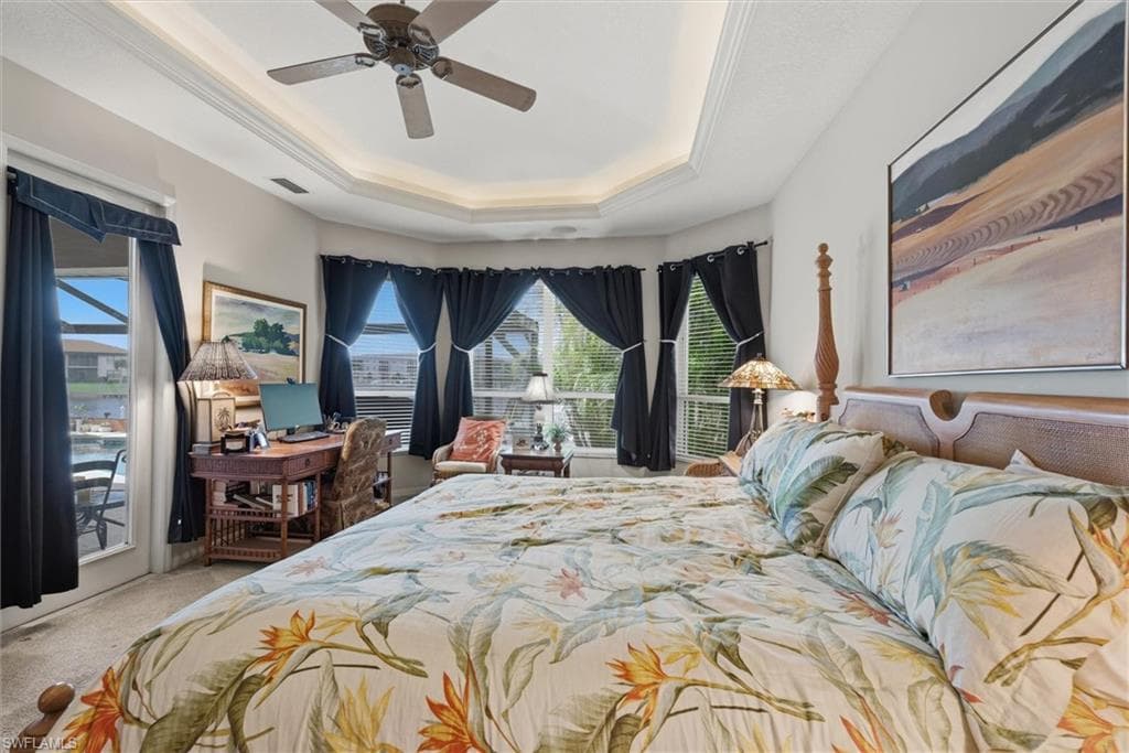 Bedroom with a ceiling fan, access to outside, a raised ceiling, light carpet, and ornamental molding