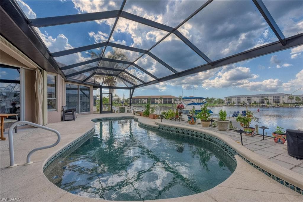 Outdoor pool featuring a sunroom, a patio, and glass enclosure