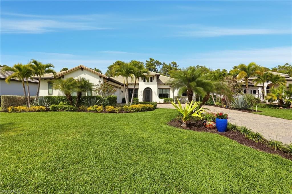 Mediterranean / spanish-style home featuring stucco siding, a front yard, and curved driveway