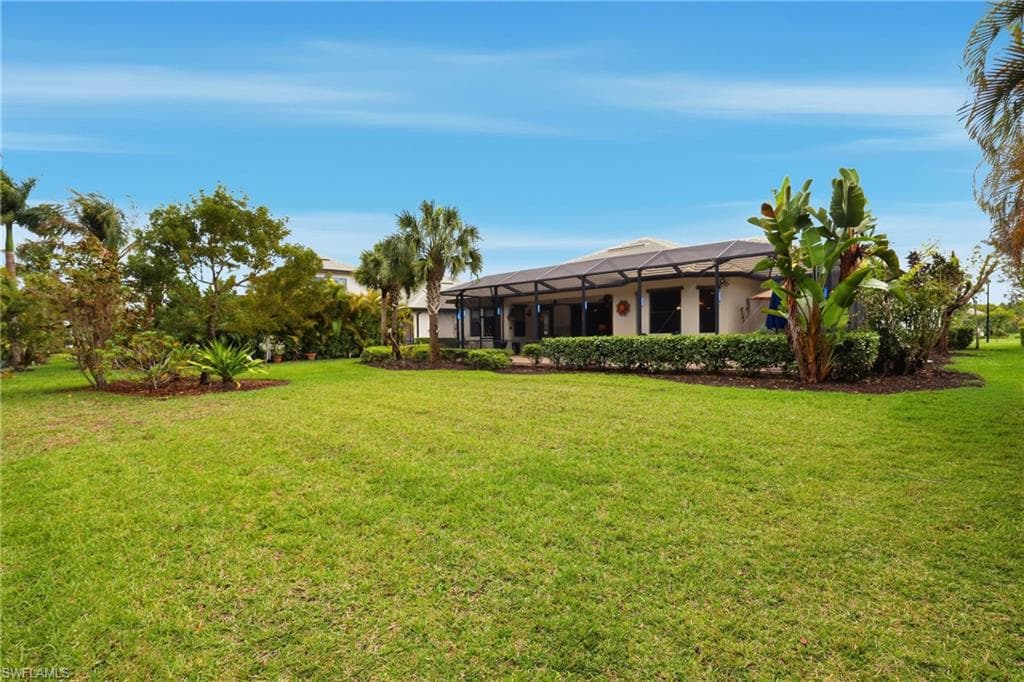 View of grassy yard with glass enclosure and a sunroom