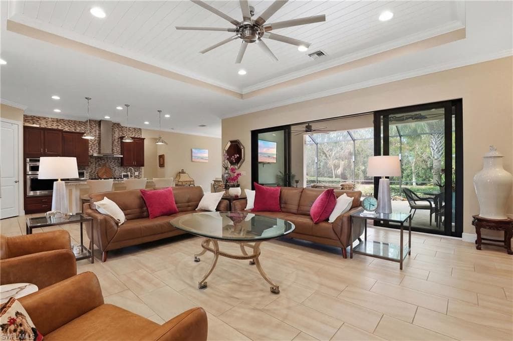 Living area featuring a raised ceiling, ceiling fan, recessed lighting, and ornamental molding