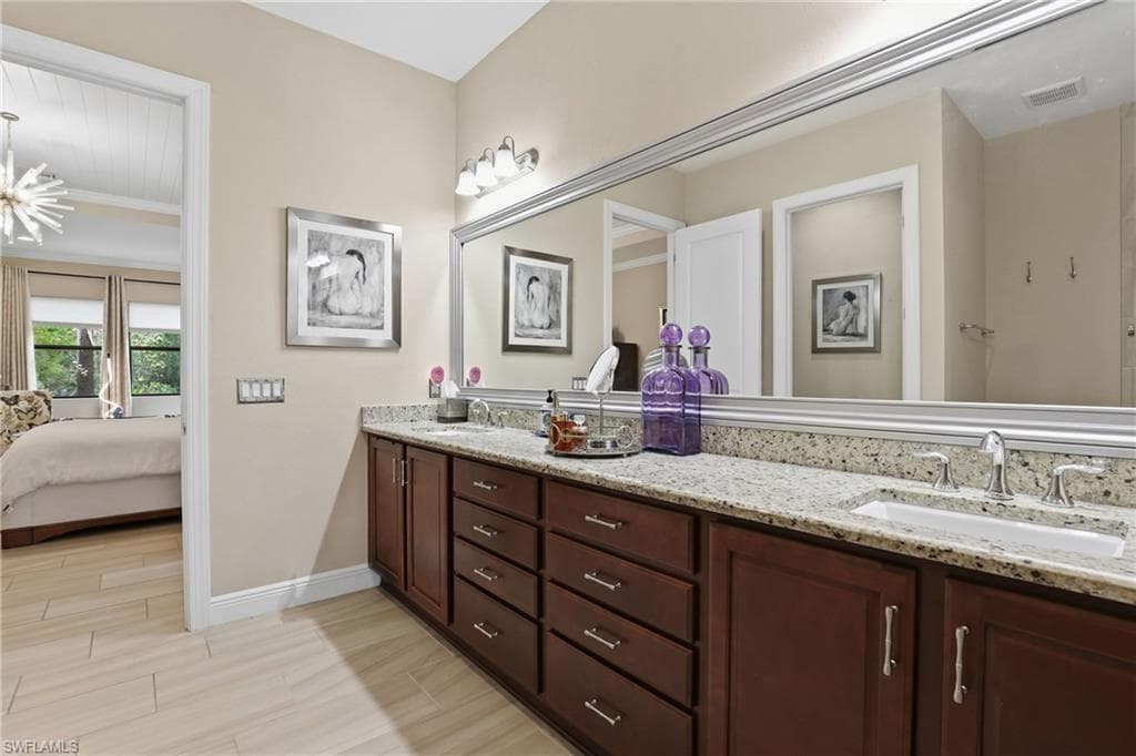 Bathroom with double vanity, ensuite bathroom, wood finish floors, and ornamental molding