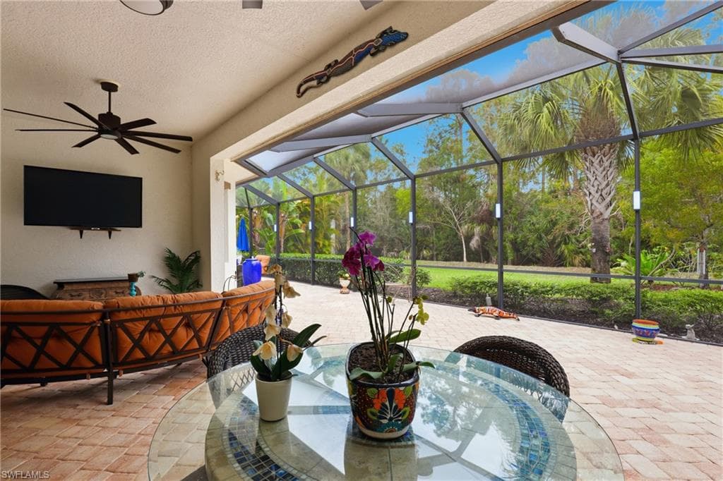 View of patio with glass enclosure, a sunroom, and outdoor furniture
