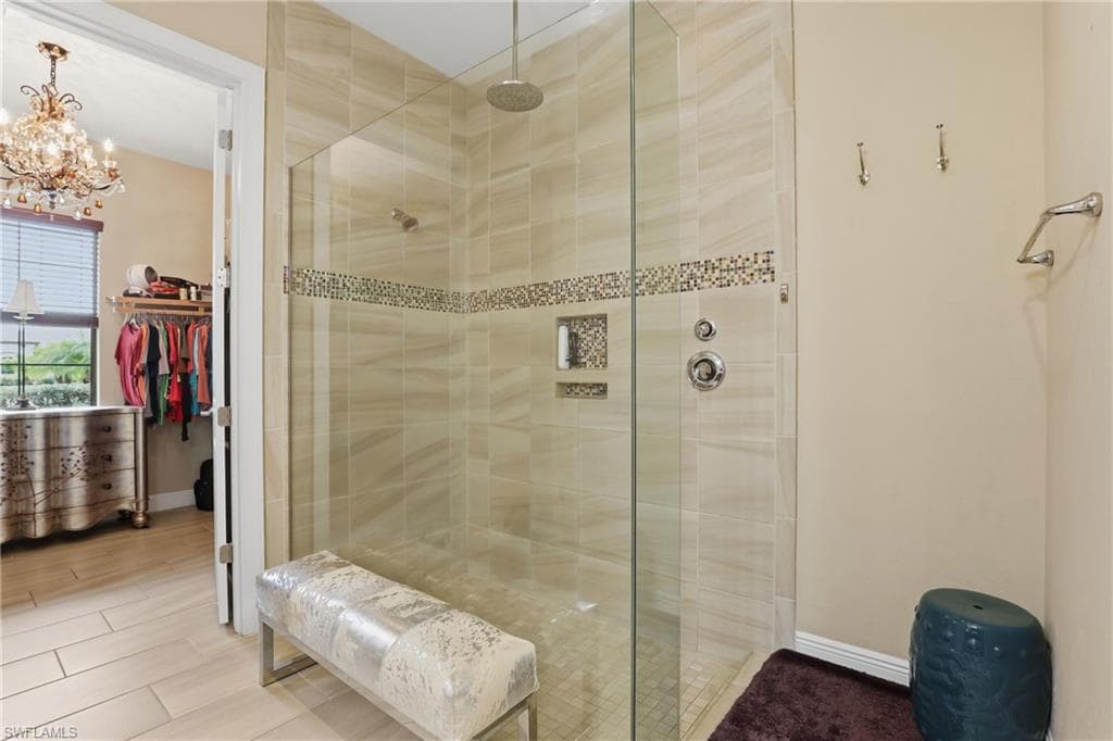 Bathroom with a stall shower, a spacious closet, and a chandelier
