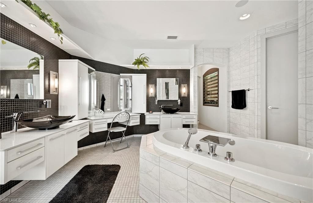 Full bath with two vanities, recessed lighting, a bath, tile walls, and decorative backsplash