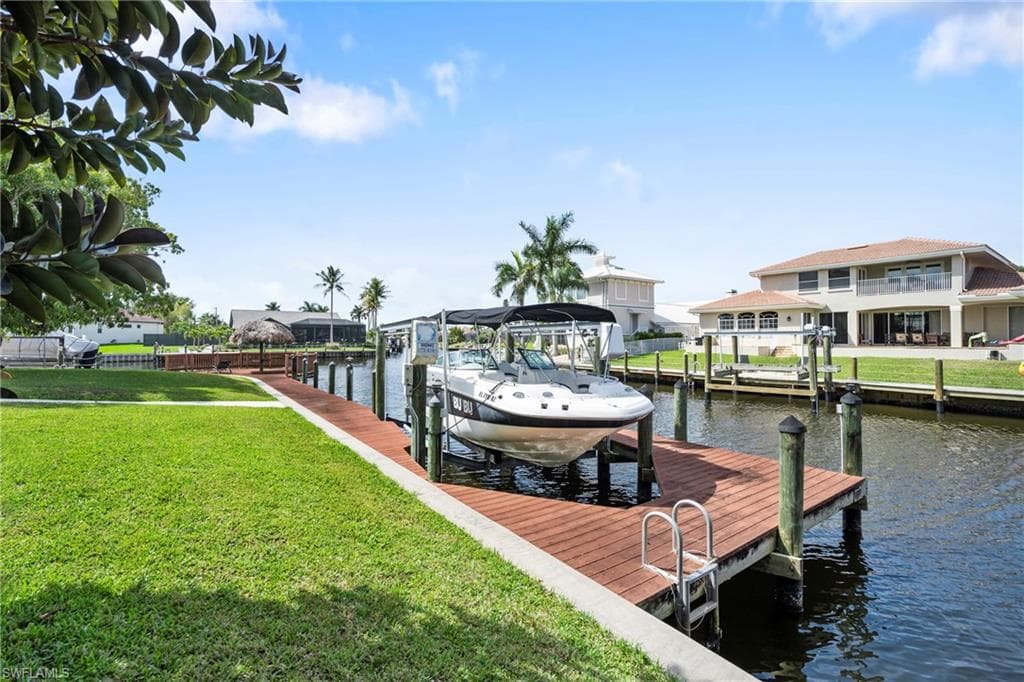 Dock with a water view, boat lift, and a yard
