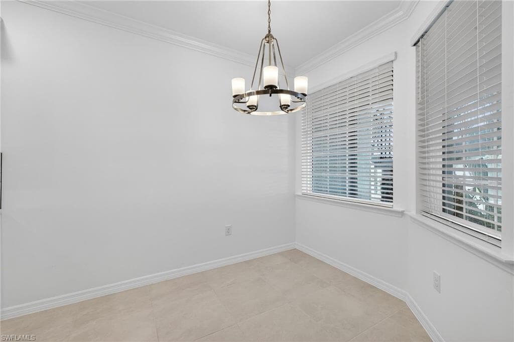 Unfurnished dining area with ornamental molding and suspended lighting