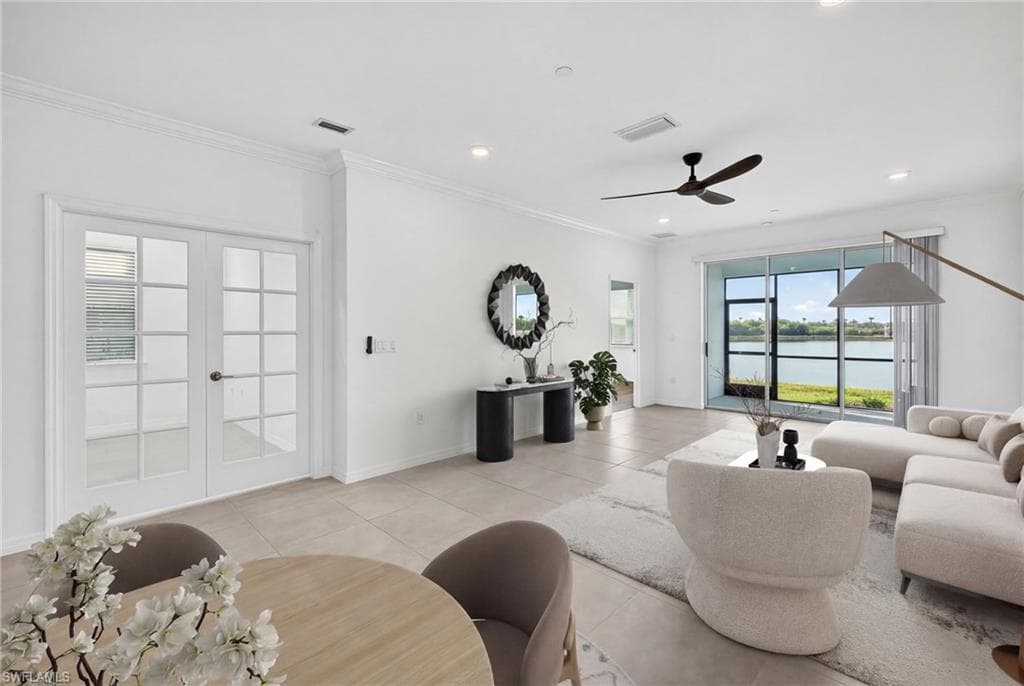 Living area featuring crown molding, french doors, light tile patterned floors, a ceiling fan, and a water view