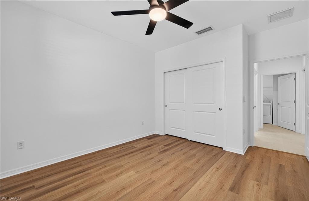Unfurnished bedroom with light wood-style flooring, a closet, ceiling fan, and washer / clothes dryer
