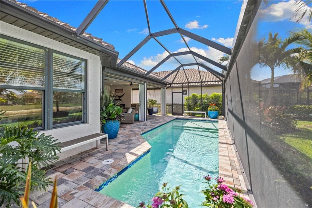 Swimming pool featuring a sunroom, glass enclosure, and a patio area
