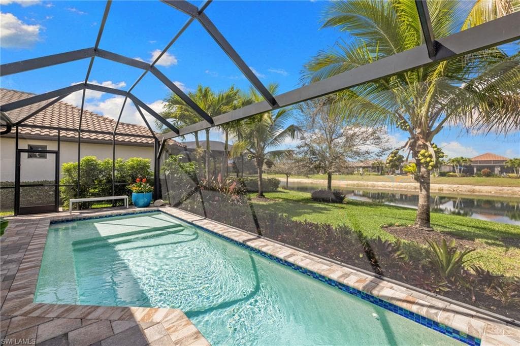 Swimming pool featuring a sunroom, a lanai, a lawn, and a water view