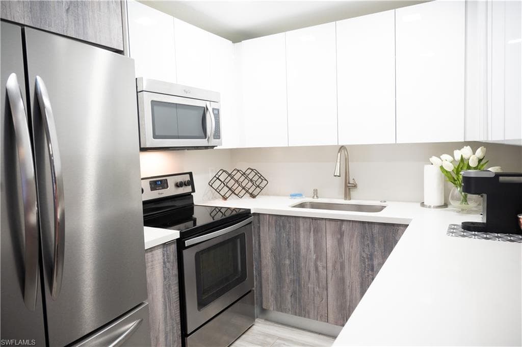 Kitchen featuring stainless steel appliances, two tone cabinets, and modern cabinets