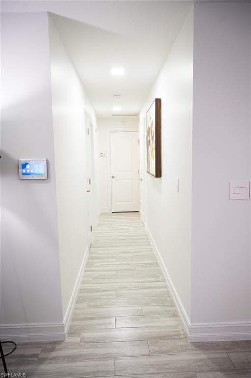 Hallway featuring light wood finished floors and baseboards