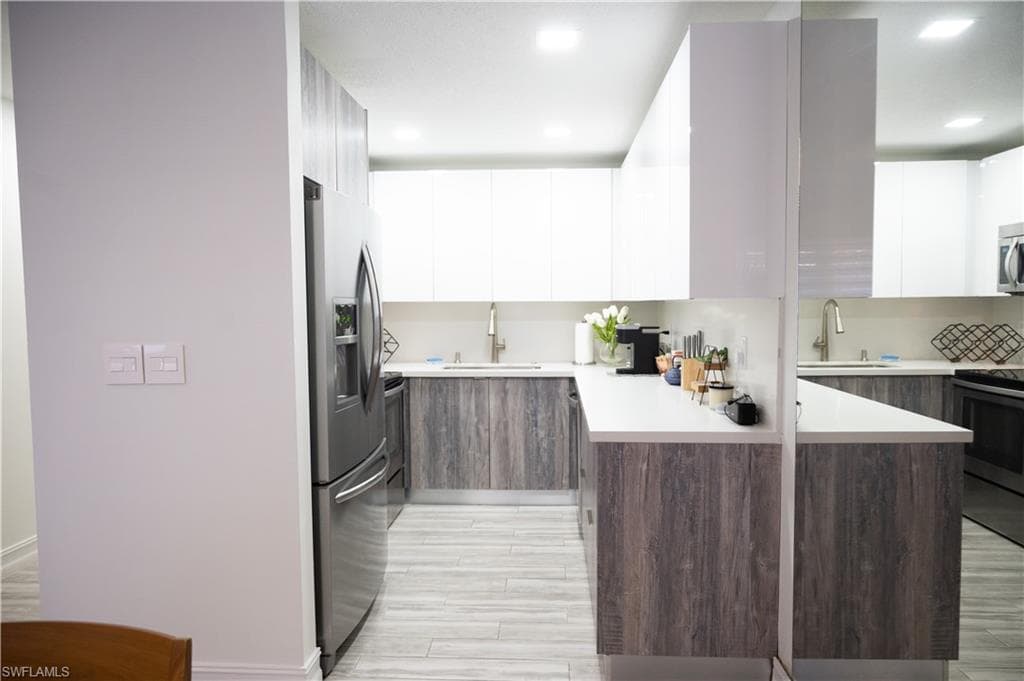 Kitchen with dual tone cabinetry, light countertops, modern cabinets, stainless steel appliances, and recessed lighting
