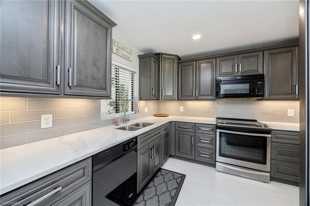 Kitchen featuring stainless steel range with electric cooktop, dishwashing machine, black microwave, light stone counters, and recessed lighting