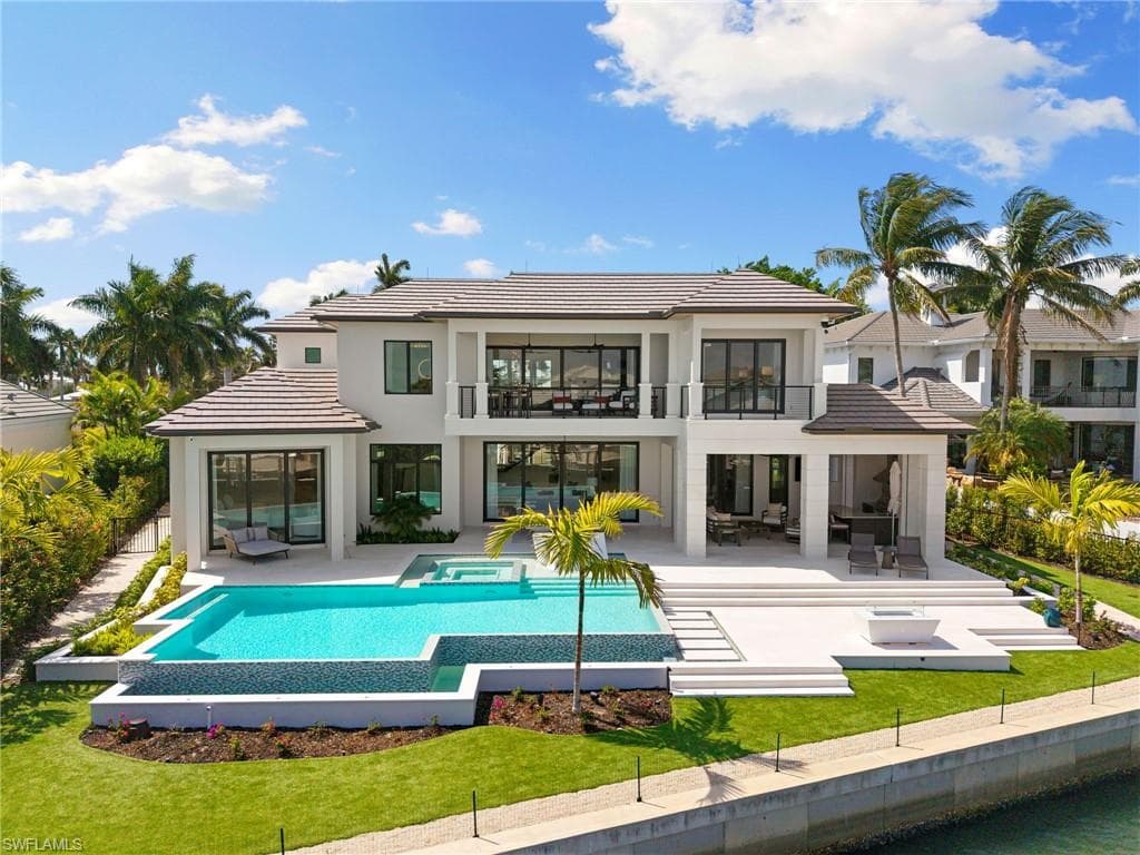 Rear view of house with a patio, an outdoor lounge area, a pool with connected hot tub, a balcony, and a tile roof
